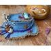 This shows the hat has a little blue bird nesting at the top. A purple rope is tied around the hat. It has a real acorn and a rusty star. 